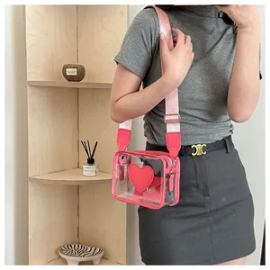 Dettaglio di una borsa a tracolla in PVC trasparente con bordi in pelle rosa e cuore