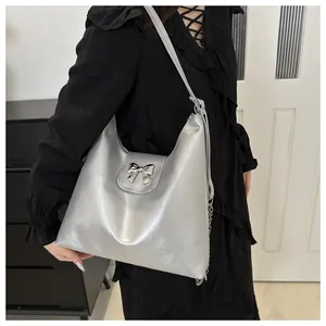 Détail du sac cabas argenté métallisé avec nœud décoratif et élégante bandoulière chaîne