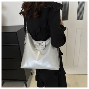 Gros plan d'un sac cabas argenté avec nœud métallique, texture brillante et chaîne chic