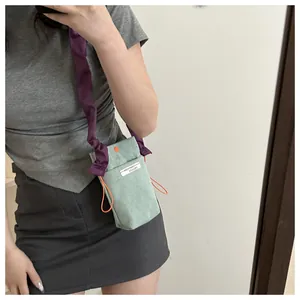 Detail view of mint green corduroy crossbody bag with purple pleated strap and orange drawstring