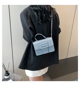 Détail du sac à bandoulière en cuir bleu clair avec boucle carrée porté par un mannequin
