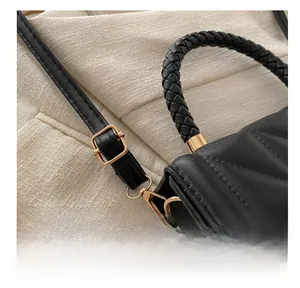 Détail du sac bandoulière matelassé noir avec boucle dorée et poignée tressée
