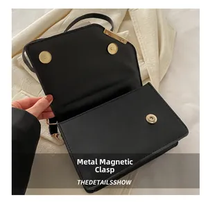 Détail du fermoir magnétique doré sur un sac à bandoulière matelassé noir
