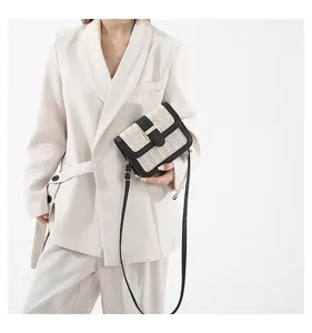 Détail du sac bandoulière bicolore en paille tressée avec bordure en similicuir noir et boucle