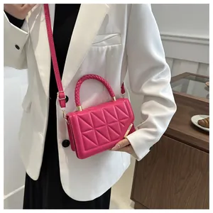 Détail du sac bandoulière fuchsia matelassé avec dorures sur une veste blanche chic