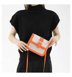 Sac bandoulière carré en paille avec bordure en cuir orange porté par un mannequin chic