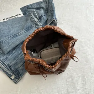 Brown faux leather drawstring bucket bag with silver chain strap and spacious interior