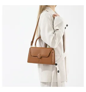 Detail view of caramel faux leather handbag with oval buckle and adjustable shoulder strap