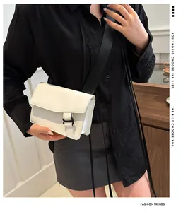 Close-up of white leather crossbody square bag with black wide strap on model