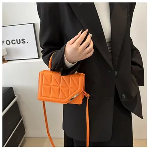 Détail du petit sac matelassé orange vif avec poignée tressée et boucle en métal doré