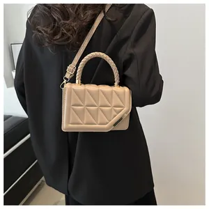 Détail d'un sac bandoulière matelassé beige à motif triangulaire et poignée tressée sur modèle