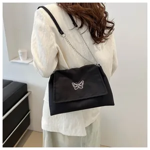 Détail du sac à bandoulière en toile noire avec broderie papillon et chaîne argentée