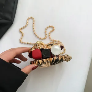 Golden shell-shaped mini handbag with beaded chain and red flocked lining for lipstick