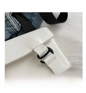 Detail shot of the white minimalist leather bag showing the black hook clasp and strap