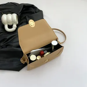 Minimalist light brown leather crossbody bag with gold lock and internal storage view