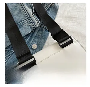 Detail view of white leather bag with black nylon wide strap and buckle on denim
