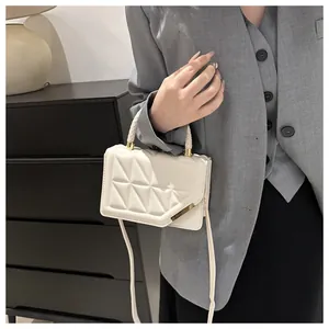 Détail d'un sac matelassé crème avec touches dorées porté par un mannequin en veste