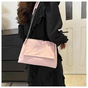Gros plan du sac sous le bras rose avec broderie papillon et détail de la chaîne en métal