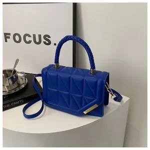 Détail du sac à main matelassé bleu roi avec poignée tressée et garniture dorée chic