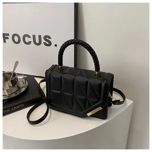 Détail d'un sac à main en cuir matelassé noir avec poignée tressée et boucles dorées