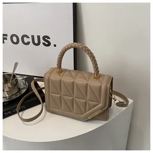 Détail du sac beige matelassé avec poignée tressée et finitions métalliques dorées