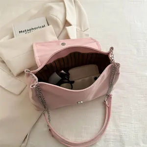 Sac à bandoulière rose avec chaîne argentée et doublure rayée montrant l'intérieur