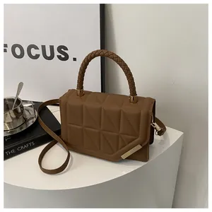 Détail du sac à main marron matelassé avec poignée tressée et finitions dorées chic