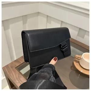 Side view of black matte leather mini square bag with wide woven strap and buckle detail