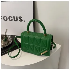Détail d'un sac à main matelassé vert avec poignée tressée et finitions dorées élégantes