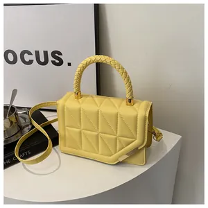 Détail du sac matelassé jaune vif avec poignée tressée sur un support blanc minimaliste