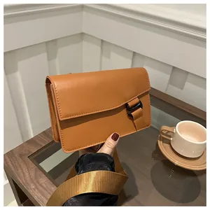 Close-up of brown crossbody square bag with wide nylon strap and black buckle detail