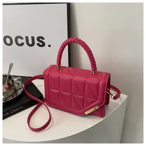 Détail du sac bandoulière matelassé rose vif avec poignées tissées et boucles dorées