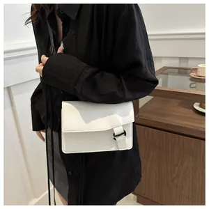 Detail of the white rectangular crossbody bag showing the D-ring buckle and fine stitching