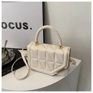 Gros plan sur le sac matelassé blanc crème avec poignée tressée et détails dorés