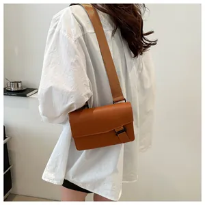 Brown rectangular crossbody bag detail with wide nylon strap and black buckle on model