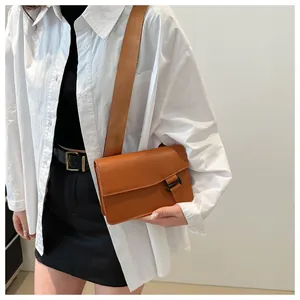 Close-up of brown crossbody bag with wide shoulder strap and minimal rectangular design