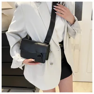 Detail of minimalist black crossbody bag with wide shoulder strap worn by a model
