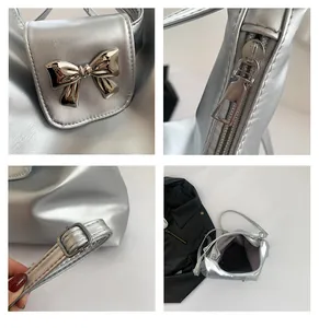Detail showing silver metallic bag bow decoration, zipper, and adjustable strap buckle