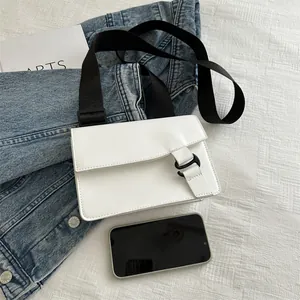 Minimalist white square flap bag with black wide strap shown next to a smartphone