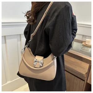 Detailaufnahme einer beigen Halbmond-Schultertasche mit silberner Schleifenschnalle und Lederriemen