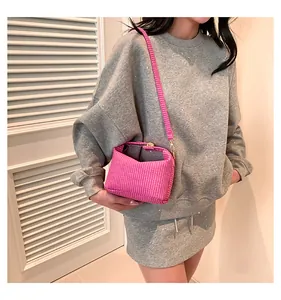 Detail der pinkfarbenen geflochtenen Mini-Tasche mit verstellbarem Gurt am Outfit
