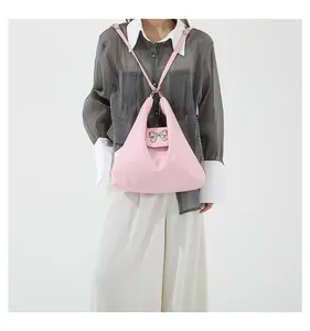 Detail of soft pink tote bag featuring a large silver metallic bow and chain strap
