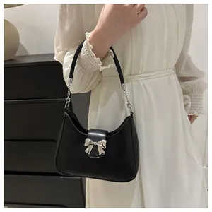 Detailansicht der schwarzen Handtasche mit Silberschleife und modischem Kettenriemen