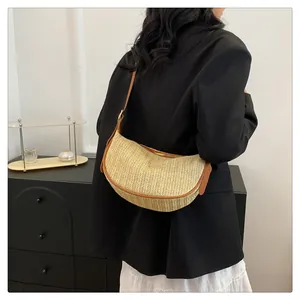 Detail of a beige woven crescent underarm bag with brown leather trim and stitching