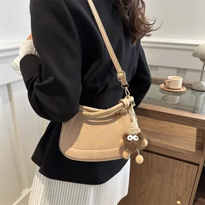 Beige minimalist suede shoulder bag with a cute plush charm and gold lettering detail