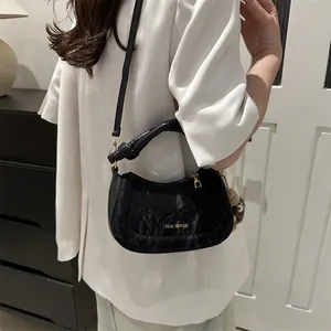 Black marble texture saddle bag with gold lettering and brown bear charm on white blazer