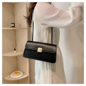 Détail d'un sac sous les aisselles noir minimaliste avec boucle dorée sur un mannequin