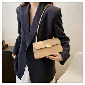 Sac bandoulière beige chic avec boucle dorée porté avec un blazer bleu