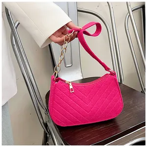 Detail of magenta felt underarm bag featuring V-shaped quilting and a chunky metal chain