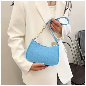 Model wearing a light blue felt underarm bag with V-shaped quilting and gold chain strap